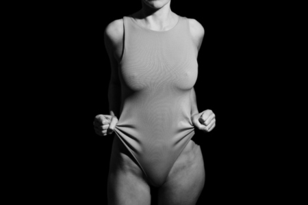 Crop anonymous woman touching bodysuit in studio