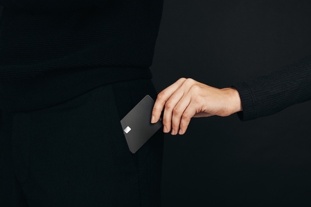 Female hand pulling a black credit card out of a pocket
