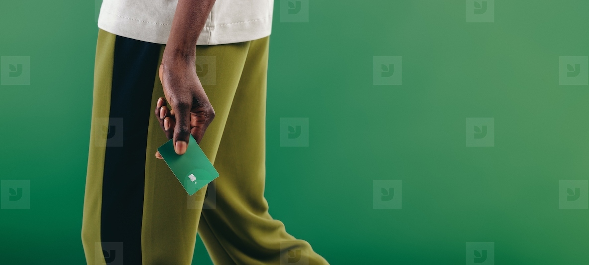 Eco friendly consumerism Man walking with a green credit card in his hand