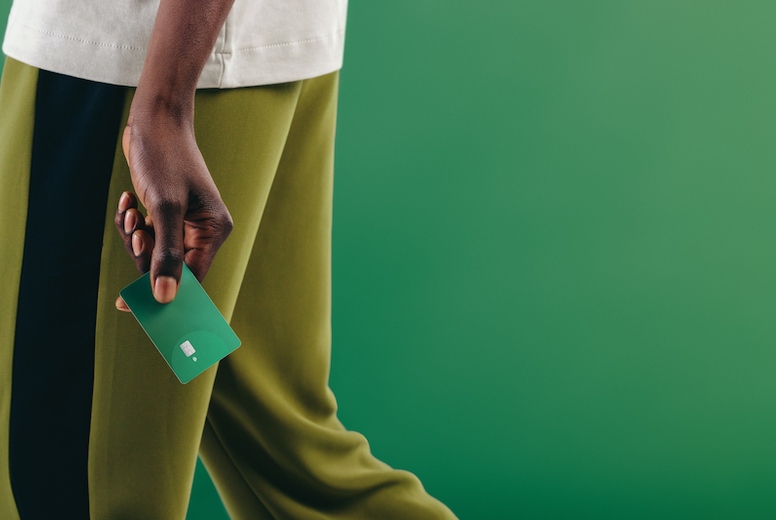 Eco-friendly consumerism Man walking with a green credit card in his hand