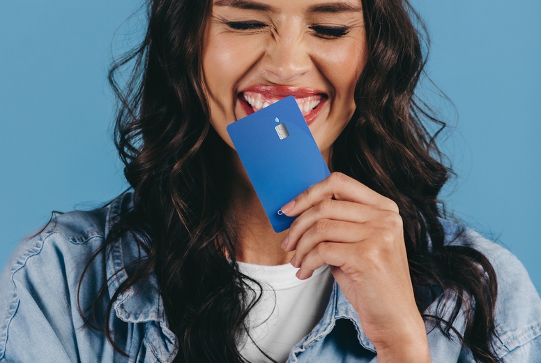 New generation of banking Excited gen z woman holds a credit card over her chin in a studio