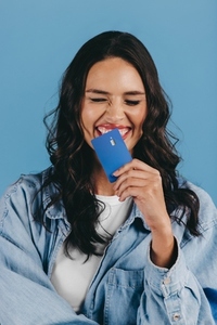 New generation of banking Excited gen z woman holds a credit card over her chin in a studio