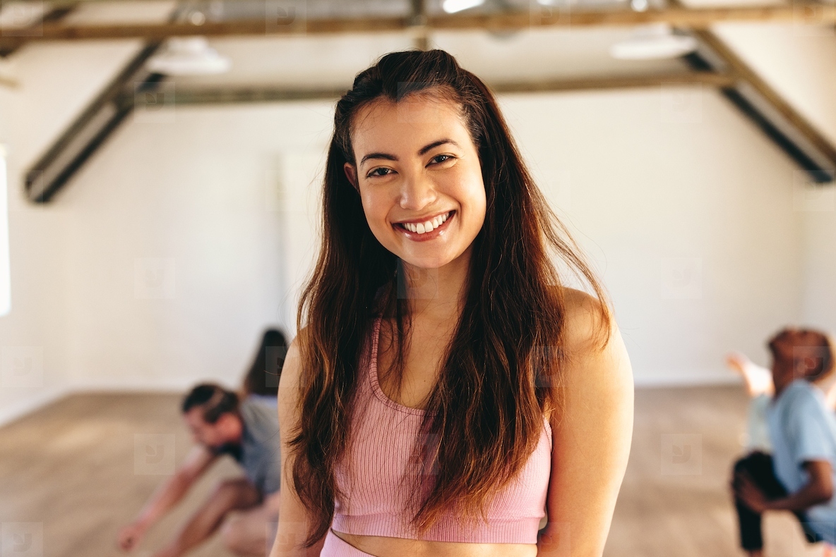 Happy yoga instructor smiling at the camera in a fitness studio