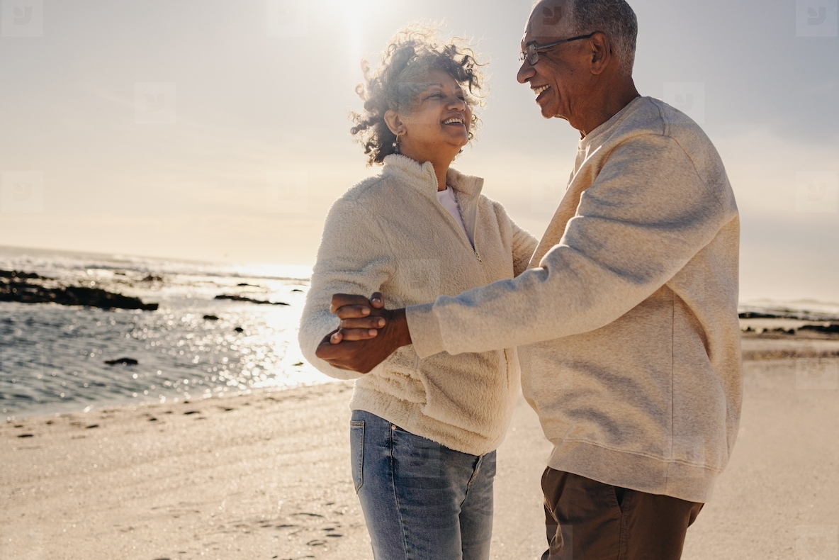 Cheerful senior couple dancing together at the beach