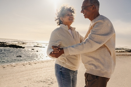Cheerful senior couple dancing together at the beach