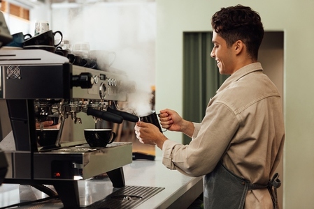 Side view of a barista using a coffee machine  Coffee shop owner preparing coffee