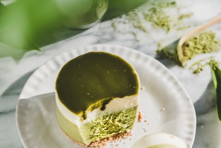 Green matcha cheesecake over grey marble background, top view
