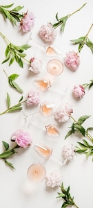 Rose wine in glasses and peony flowers over white background