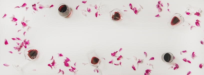 Glasses with red wine and pink flowers  copy space