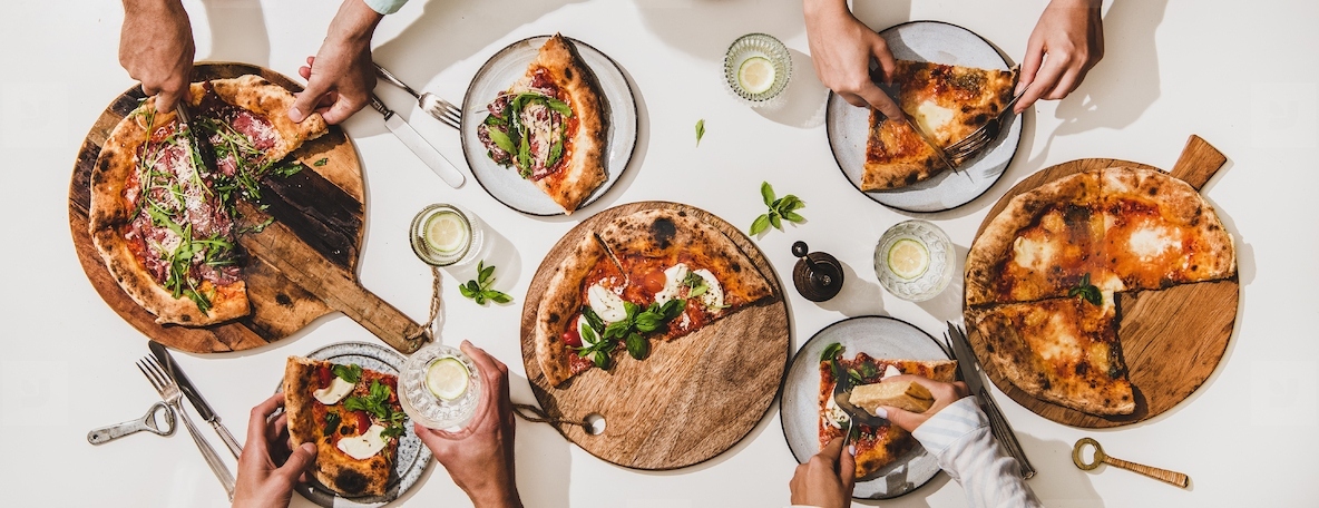 Flat lay of various pizzas  drinks and peoples hands eating pizza