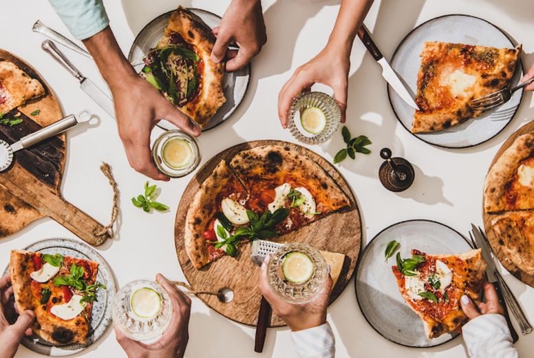 Flat-lay of various pizzas, drinks and people celebrating