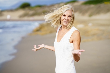 Happy mature woman walking on the beach  spending her leisure time  enjoying her free time