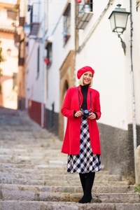 Stylish travelling lady standing on stairs in town and smiling