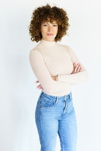 Confident curly haired woman with crossed arms