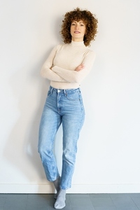 Confident woman standing against wall with crossed arms