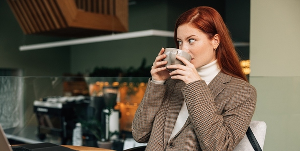 Woman in blazer drinking coffee at coffee shop