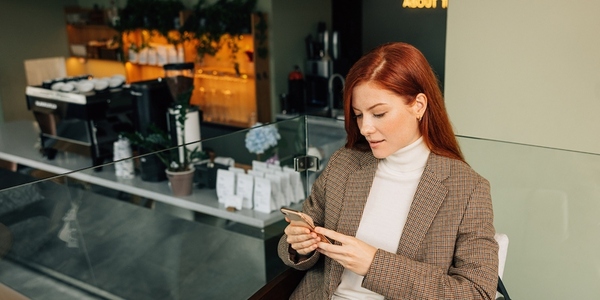 Beautiful female with ginger hair holding a mobile phone  Businesswoman in formal wear typing on a mobile phone