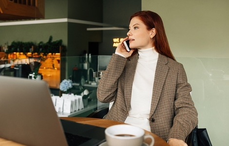 Businesswoman in formal wear talking on mobile phone while sitting in cafe