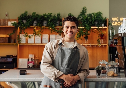 Smiling male waiter in an apron  Portrait of a handsome barista at the counter