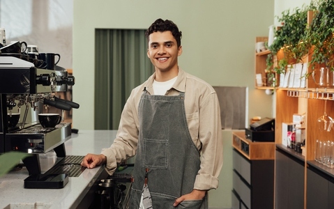 Smiling male barista in a cafe  Portrait of a cheerful man in an apron working as a barista