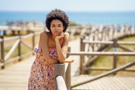 Black woman resting on wooden path near beach