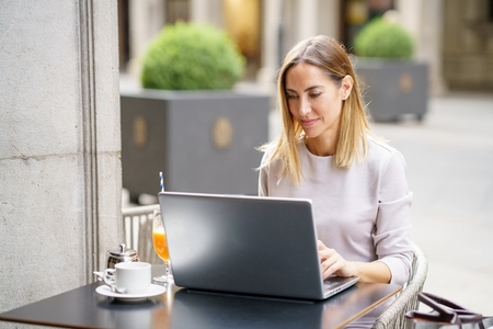 Smiling self employed woman using laptop in cafe