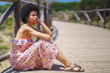 Thoughtful black woman sitting on boardwalk