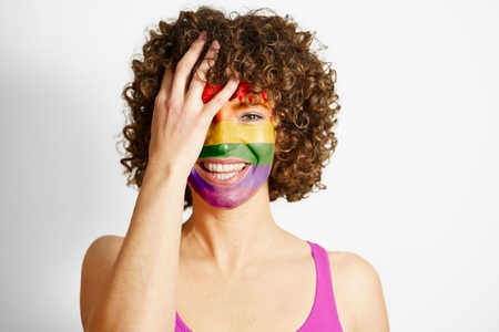 Smiling woman with face painted in rainbow colors