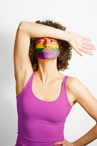 Woman with face painted in LGBT colors against white background