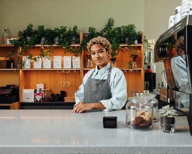 Portrait of a young and confident coffee shop owner at the counter looking at camera