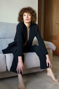 Gorgeous woman in suit with bare chest sitting on couch