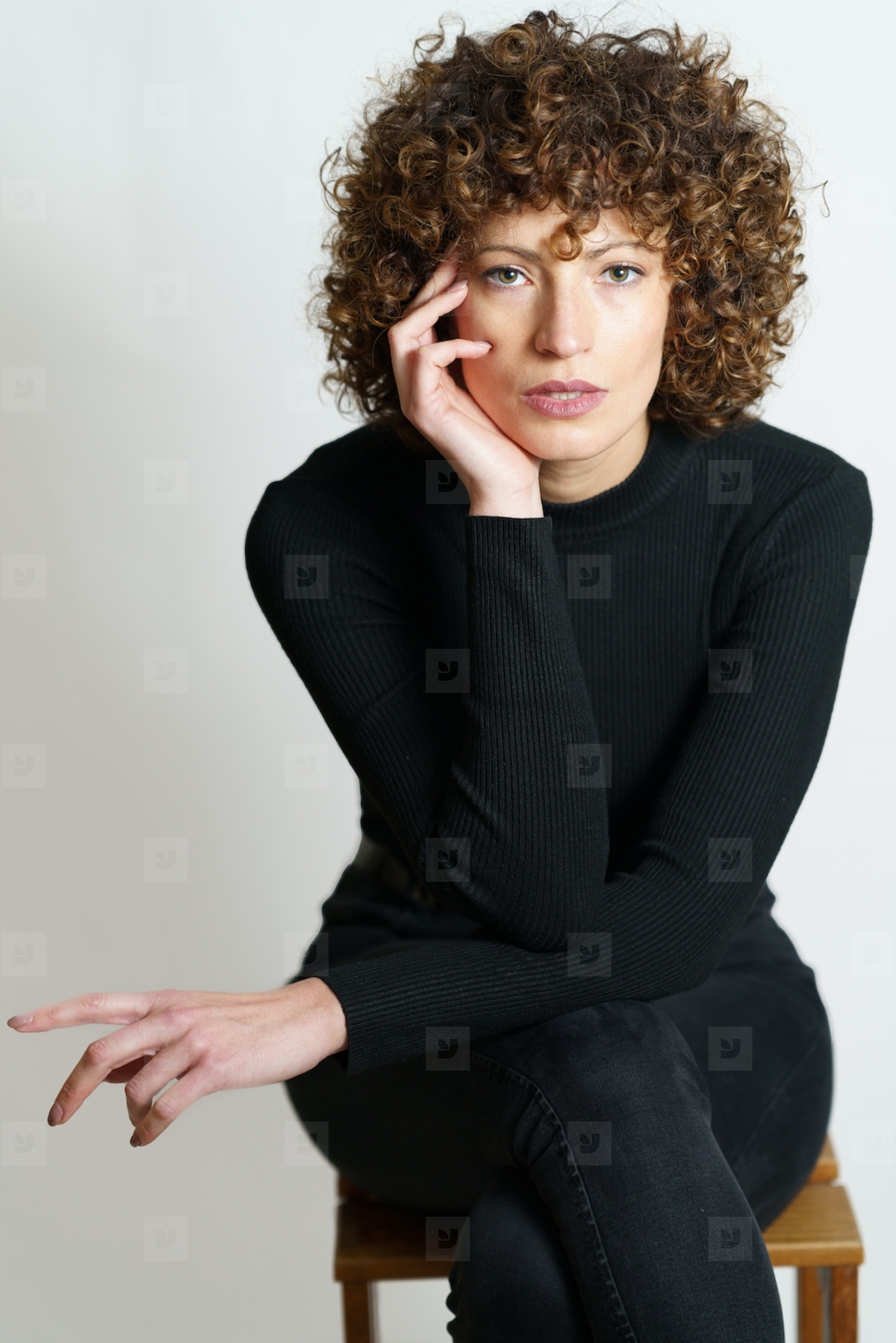 Focused curly haired woman sitting on wooden chair