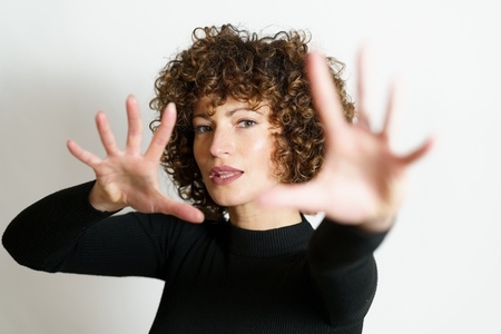 Focused woman stretching arms and showing stop gesture with full open palms
