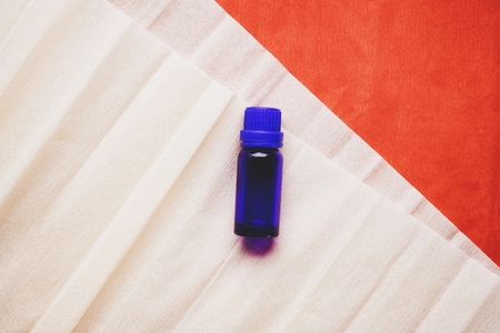 Flat lay background image of a dark blue bottle of essential oil