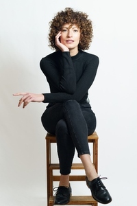 Focused curly haired woman sitting on wooden chair