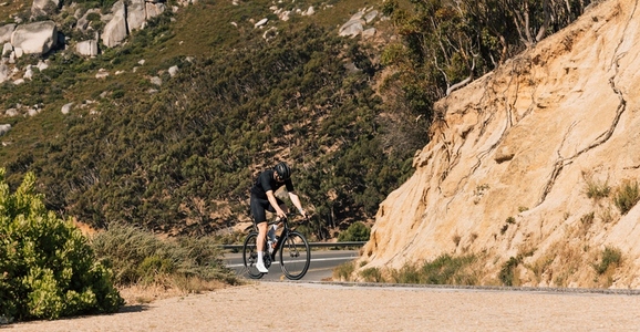 Young male cyclist practicing on an empty road in wild terrain