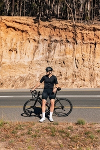 Full length of a young male cyclist relaxing on an empty road with a bicycle
