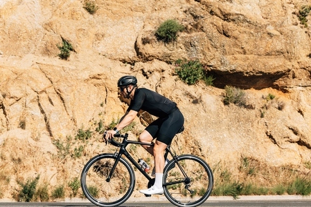 Side view of a male cyclist on a road bike against mountain
