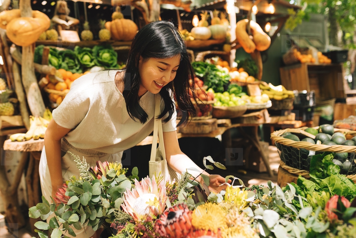 Young Asian woman choosing flowers on an outdoor market