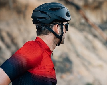 Back view of a cyclist in a black helmet looking away