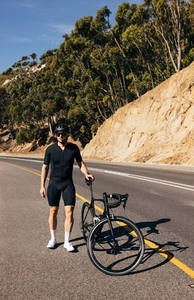 Professional cyclist with his road bike on an empty road  Man walking with bicycle