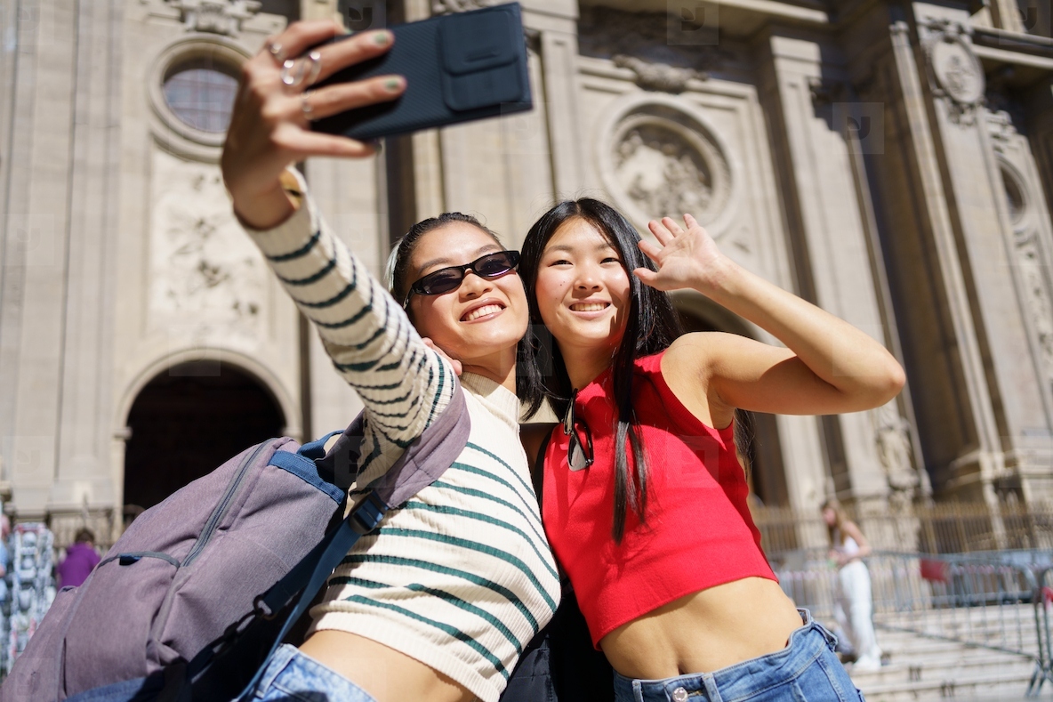 Happy Asian women taking self portrait on smartphone against ancient building
