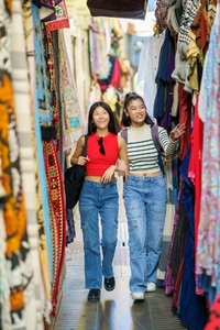 Female tourists shopping clothes in street bazaar