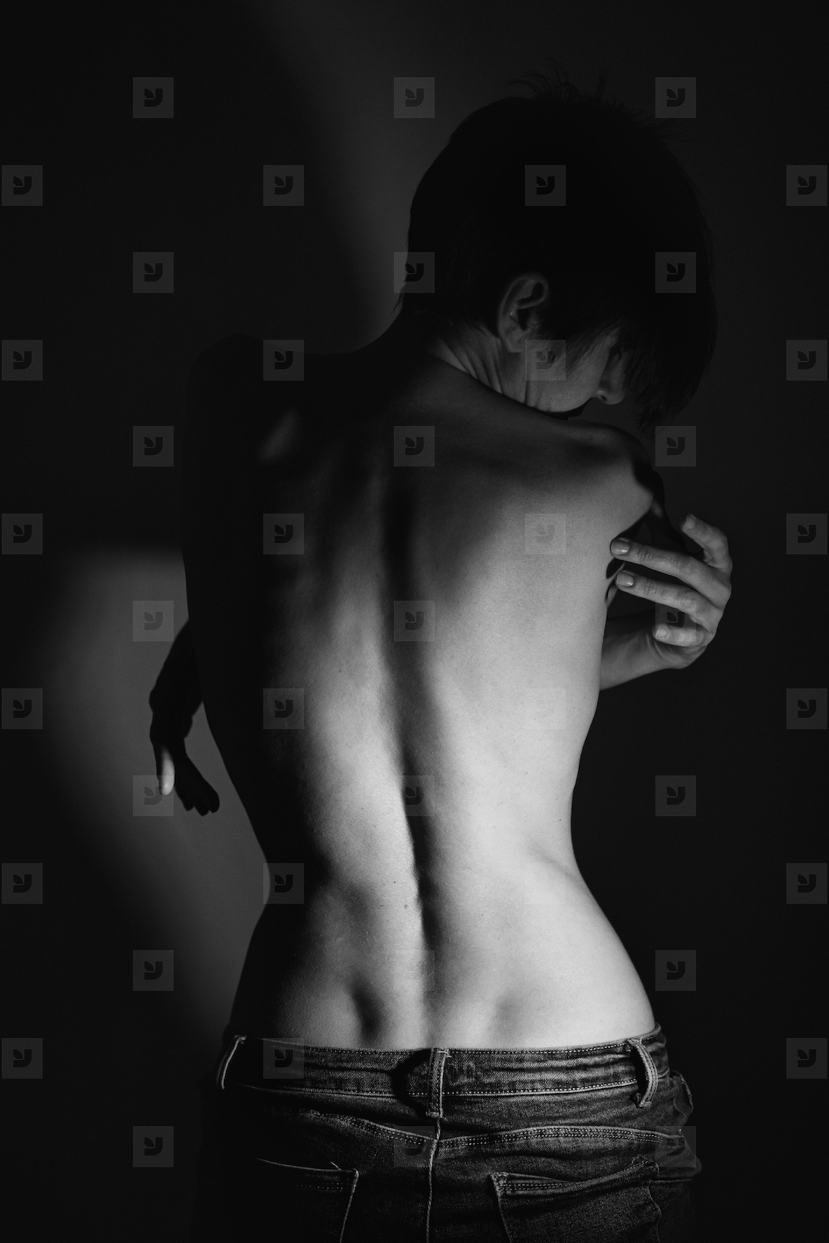 Topless calm female with folded arms standing near wall