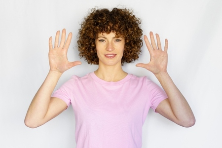 Adult woman with curly hair showing palms in studio