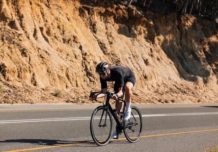 Professional road bike rider practicing on an empty road  Cyclist in a helmet and glasses on a bicycle