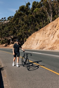 Male in fitness attire walking with his bike on the roadside