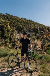 Athlete with his road bike standing in wild terrain looking into the distance