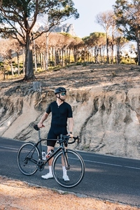 Male cyclist on a roadside with his bicycle  Professional triathlete relaxing