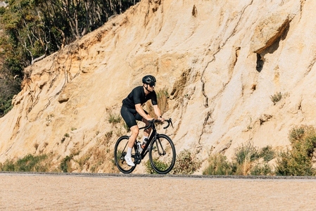 Triathlete riding his road bike on an empty road  Sportsman exercising on bicycle outdoors
